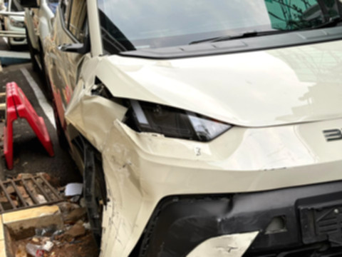 Mobil BYD merah terparkir di tengah jalan dengan kerusakan di bagian depan, dikelilingi kendaraan lain yang juga rusak.